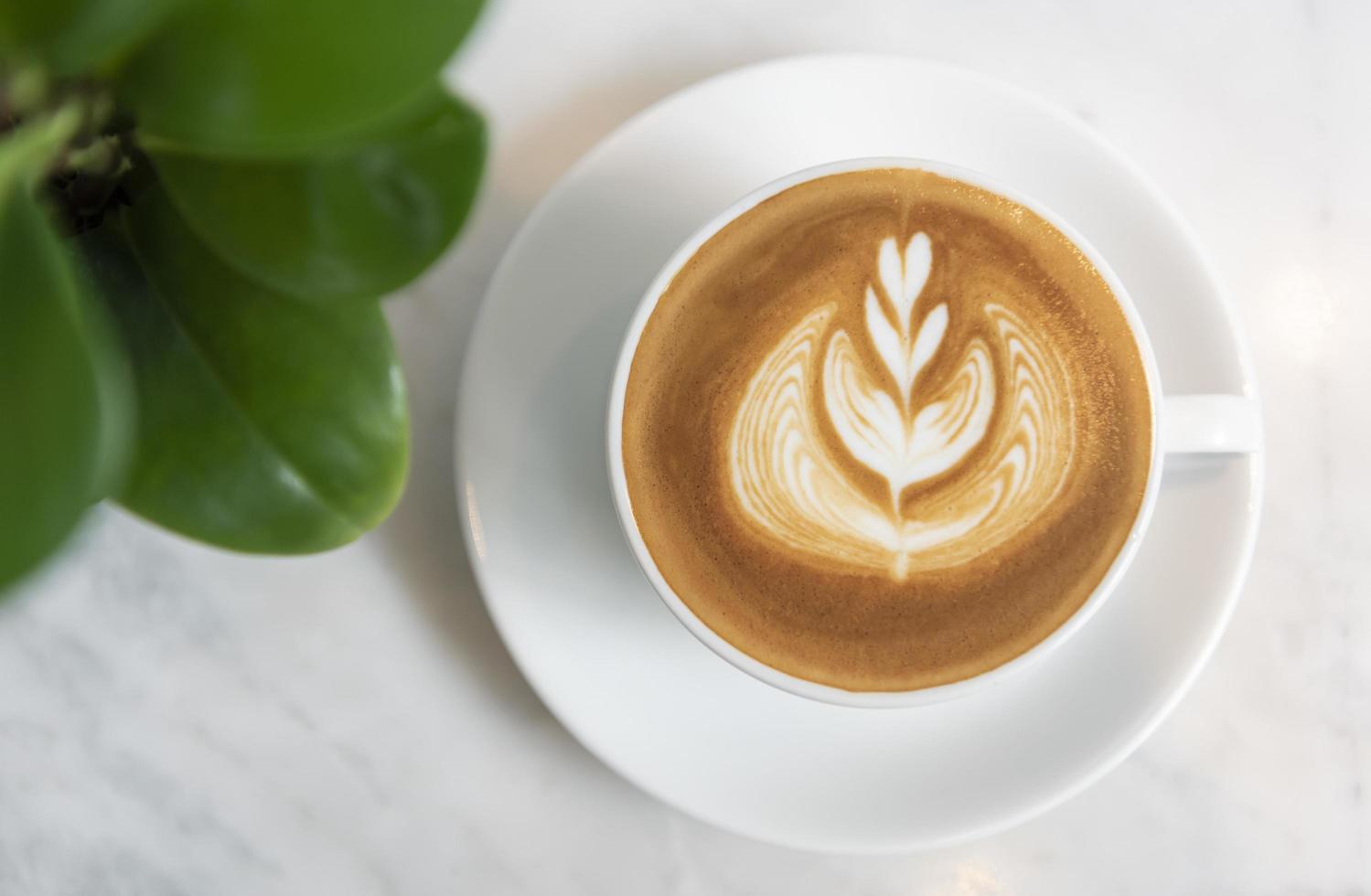 café con leche o capuchino con espuma espumosa, vista superior de la taza de café en la mesa de café. foto