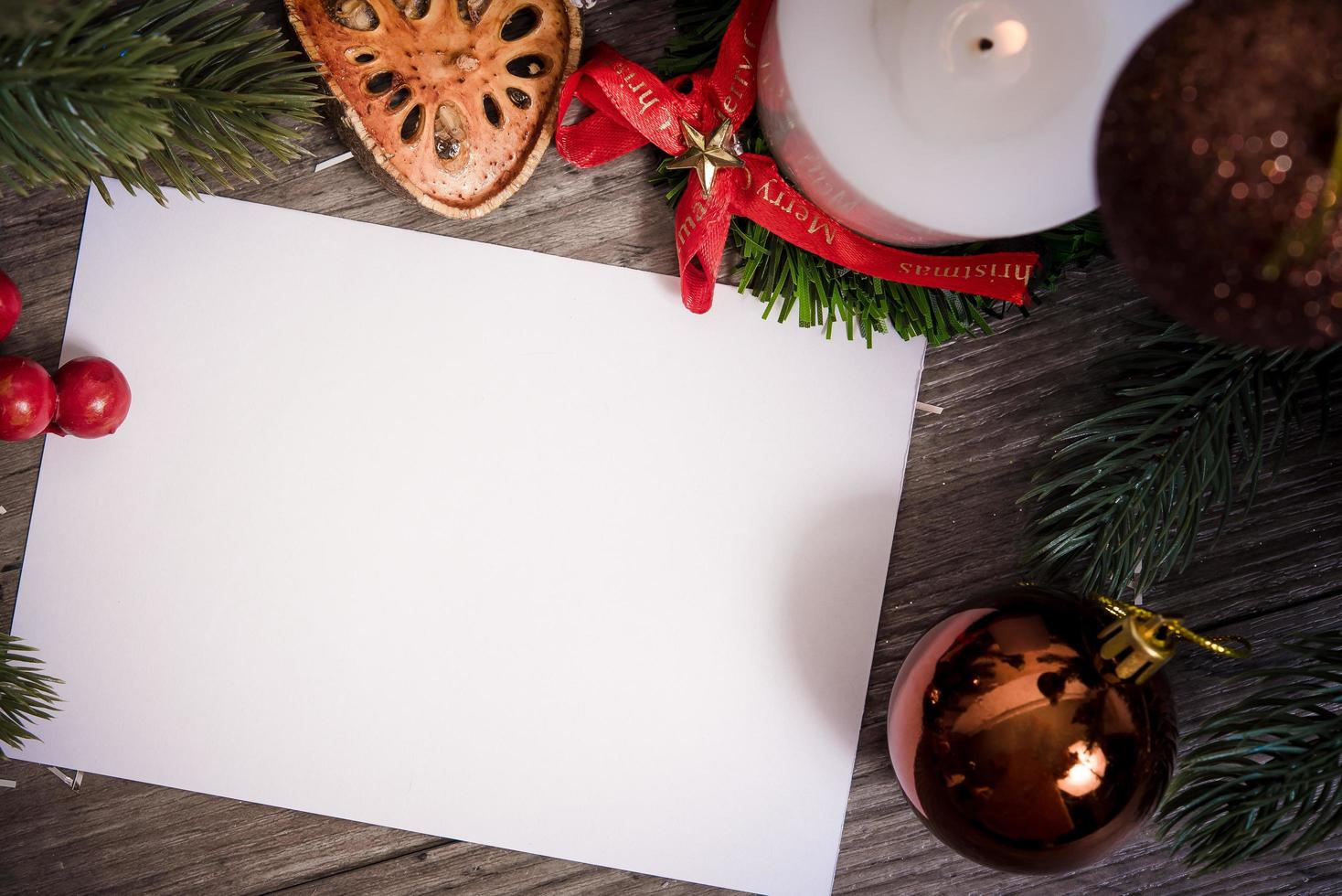 Maqueta de diseño de tarjeta de papel de felicitación navideña con decoración en mesa de madera. foto