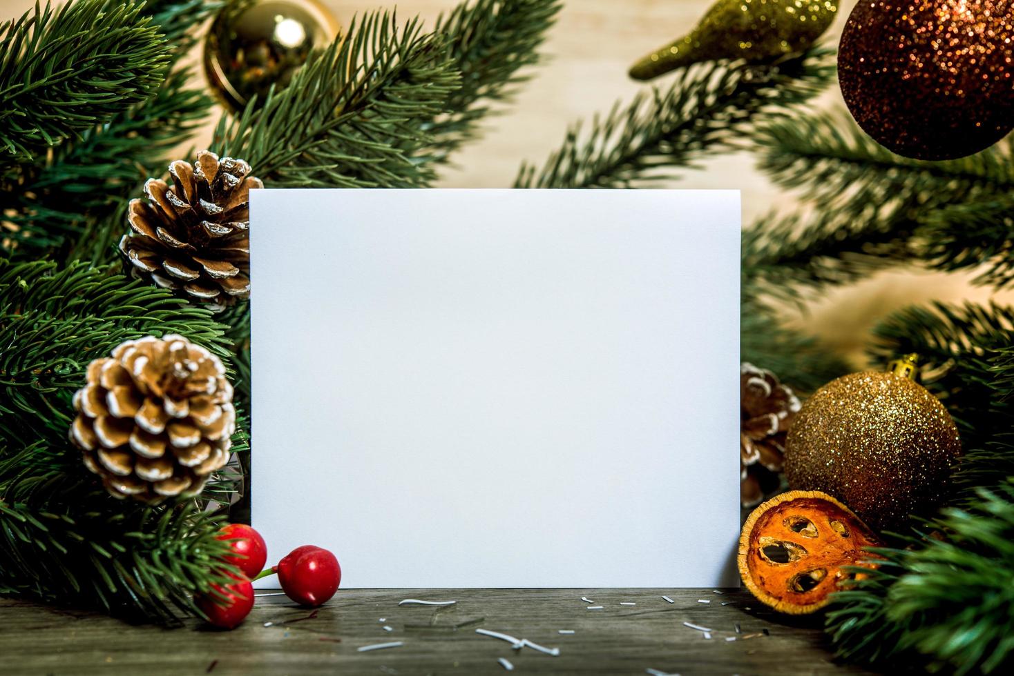 Maqueta de diseño de tarjeta de papel de felicitación navideña con decoración en mesa de madera. foto