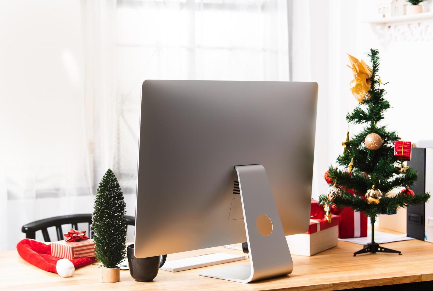 escritorio de oficina o lugar de trabajo con computadora moderna y decoración de caja de regalo de Navidad. foto