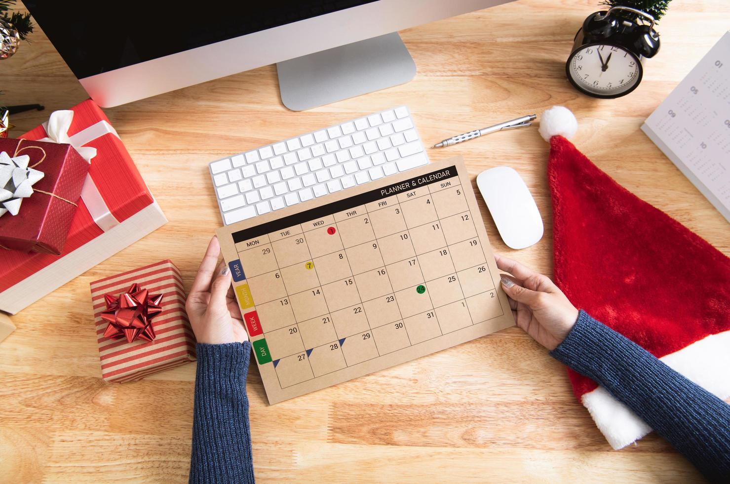 empresaria sosteniendo el planificador de calendario en vacaciones de Navidad en la oficina con decoración navideña en la mesa. foto