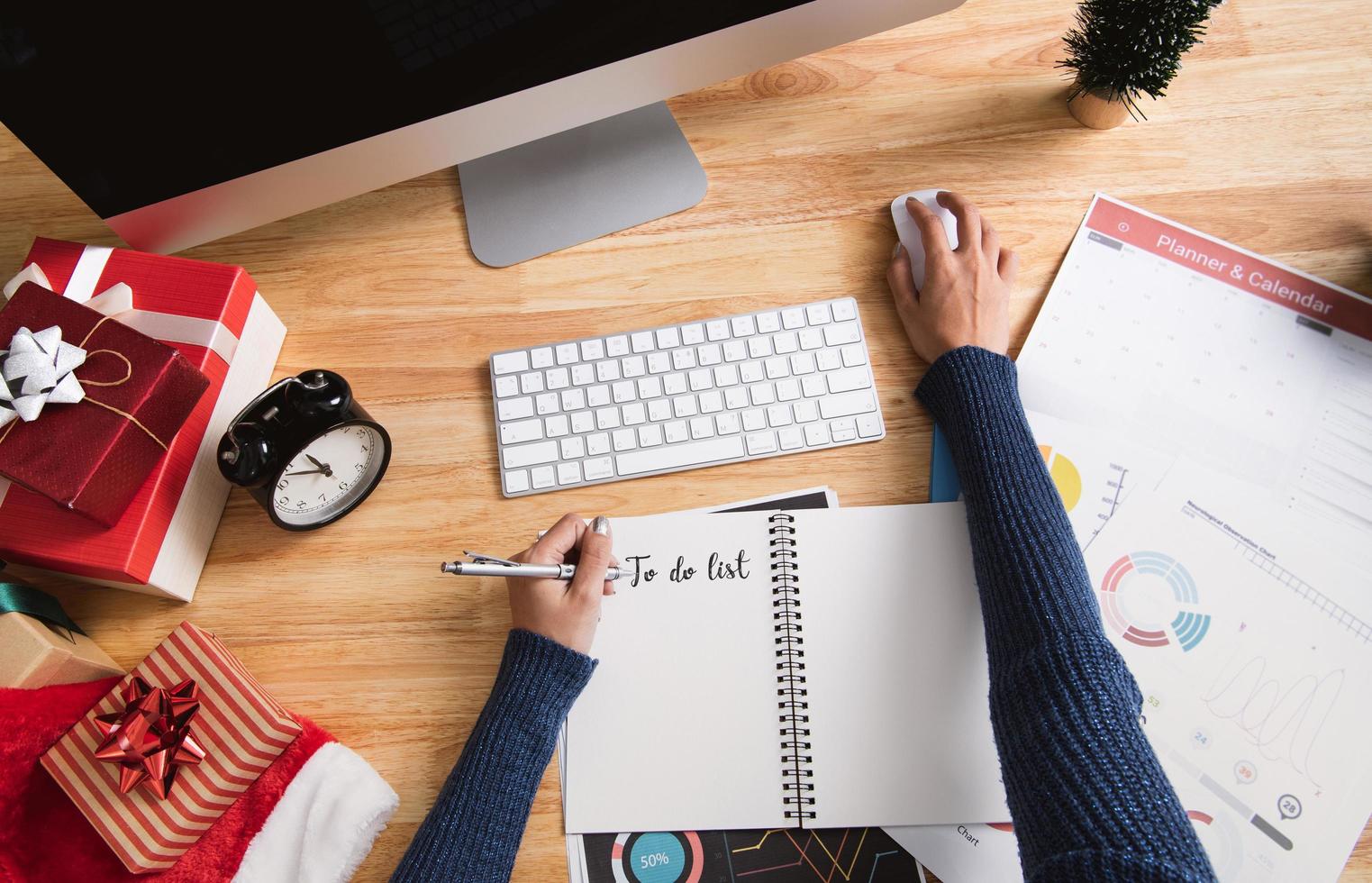 empresaria escribiendo para hacer la lista en vacaciones de Navidad en la oficina con decoración navideña en la mesa. foto