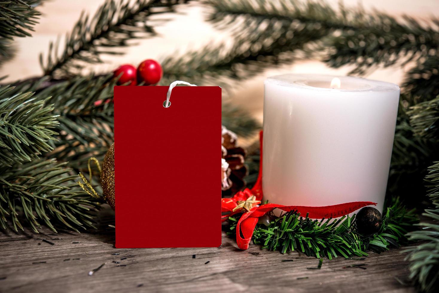 mockup tag paper card with candle christmas decoration on wood table background. photo