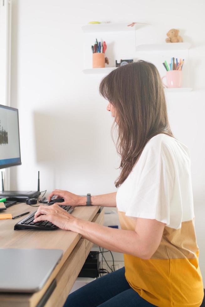 Attractive woman working at home. Wooden desk and ergonomic kneeling chair photo