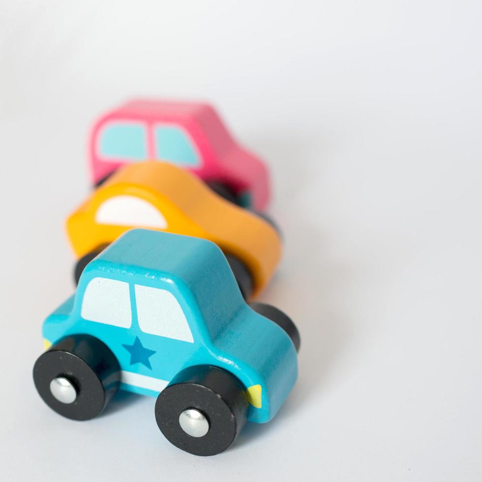 Tres coloridos coches de juguete en una fila, fondo blanco. foto