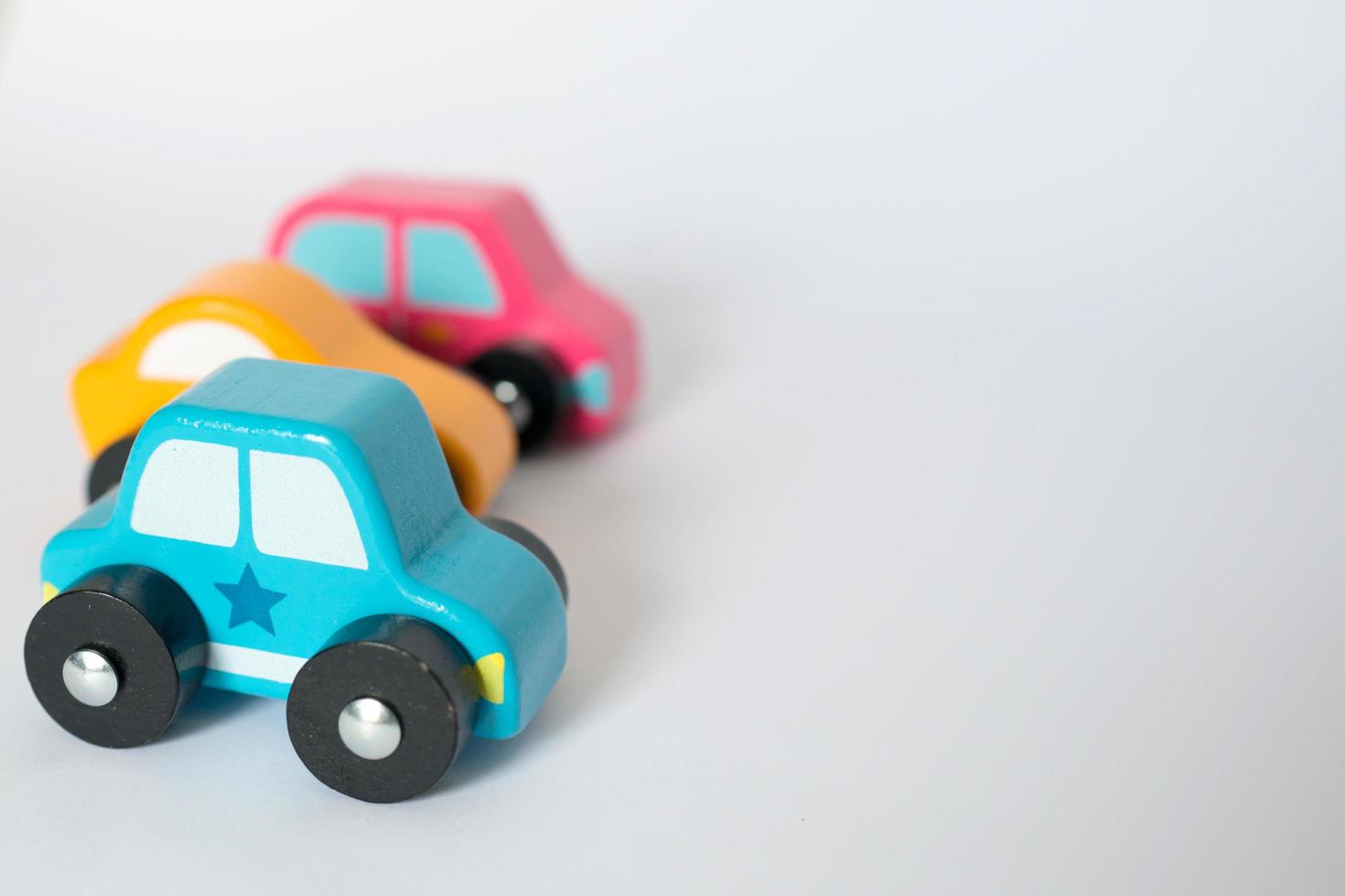 Wooden toy cars with blue, yellow and pink colors, white background photo