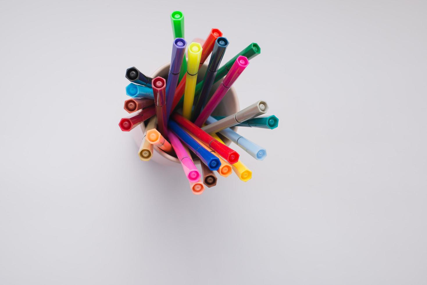 Cup full of markers seen from above. White background photo