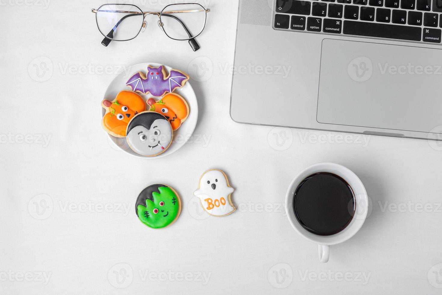 galletas de Halloween, café caliente y computadora portátil sobre fondo blanco. feliz halloween, compras en línea, hola octubre, otoño otoño, concepto festivo, fiesta y vacaciones foto