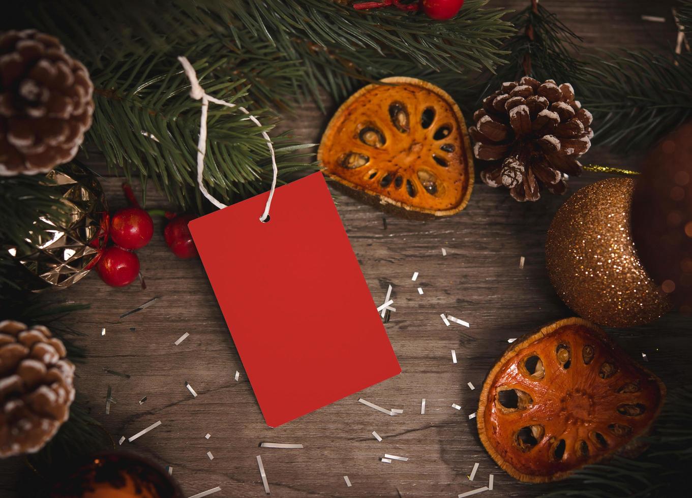 Tarjeta de papel de etiqueta de maqueta con decoración de Navidad de conos de pino sobre fondo de mesa de madera. foto