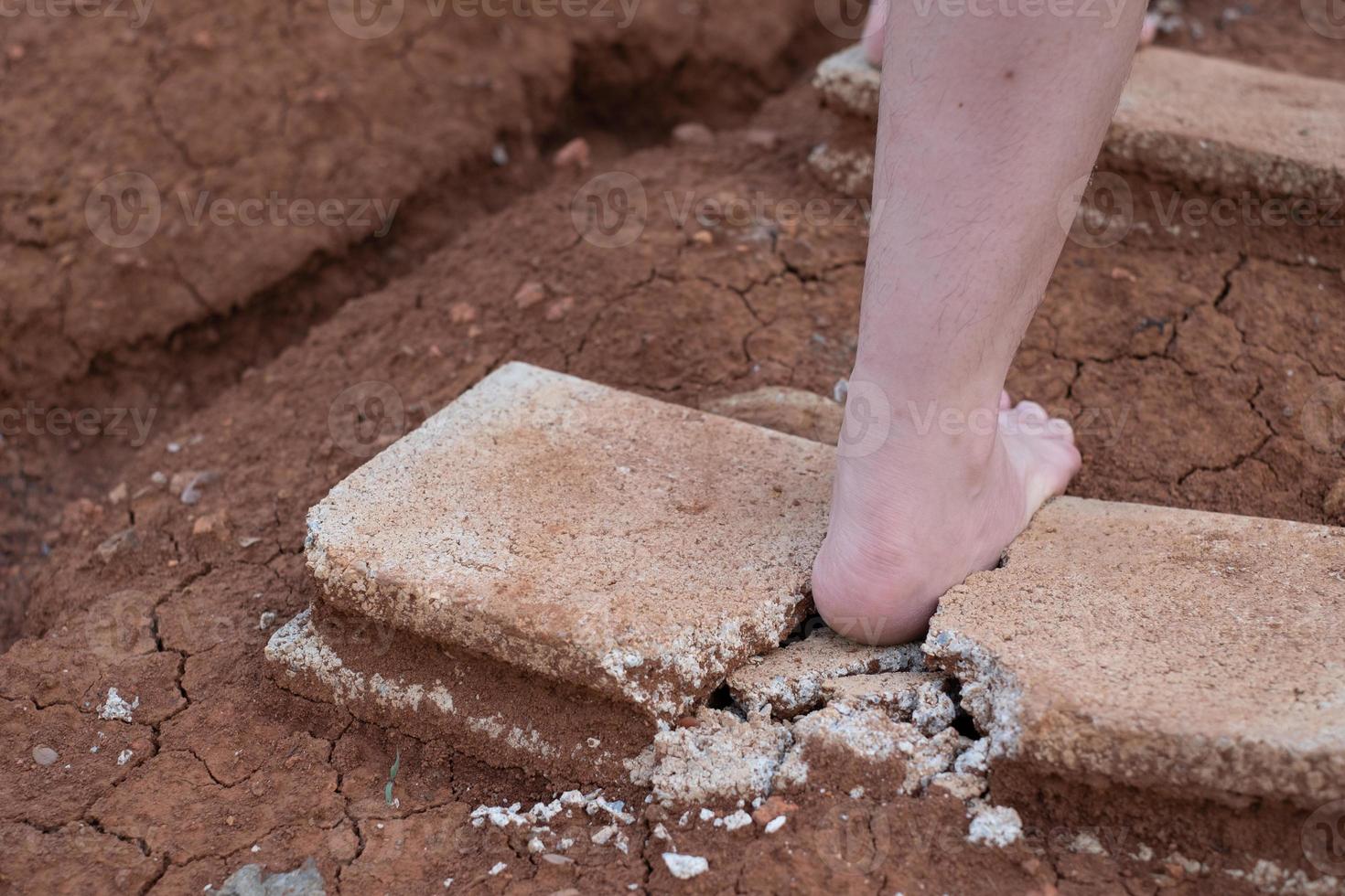 Photo close up of shards of a broken concrete block at woman barefoot at the walking