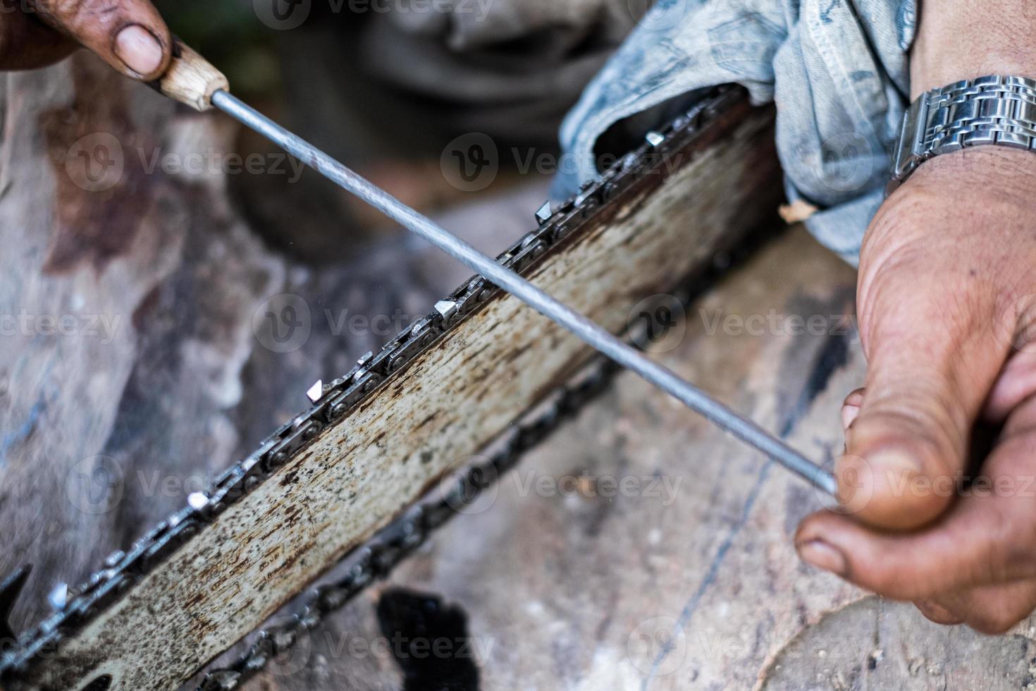 Close up man hands use a rasp to sharpen the blade chainsaw photo