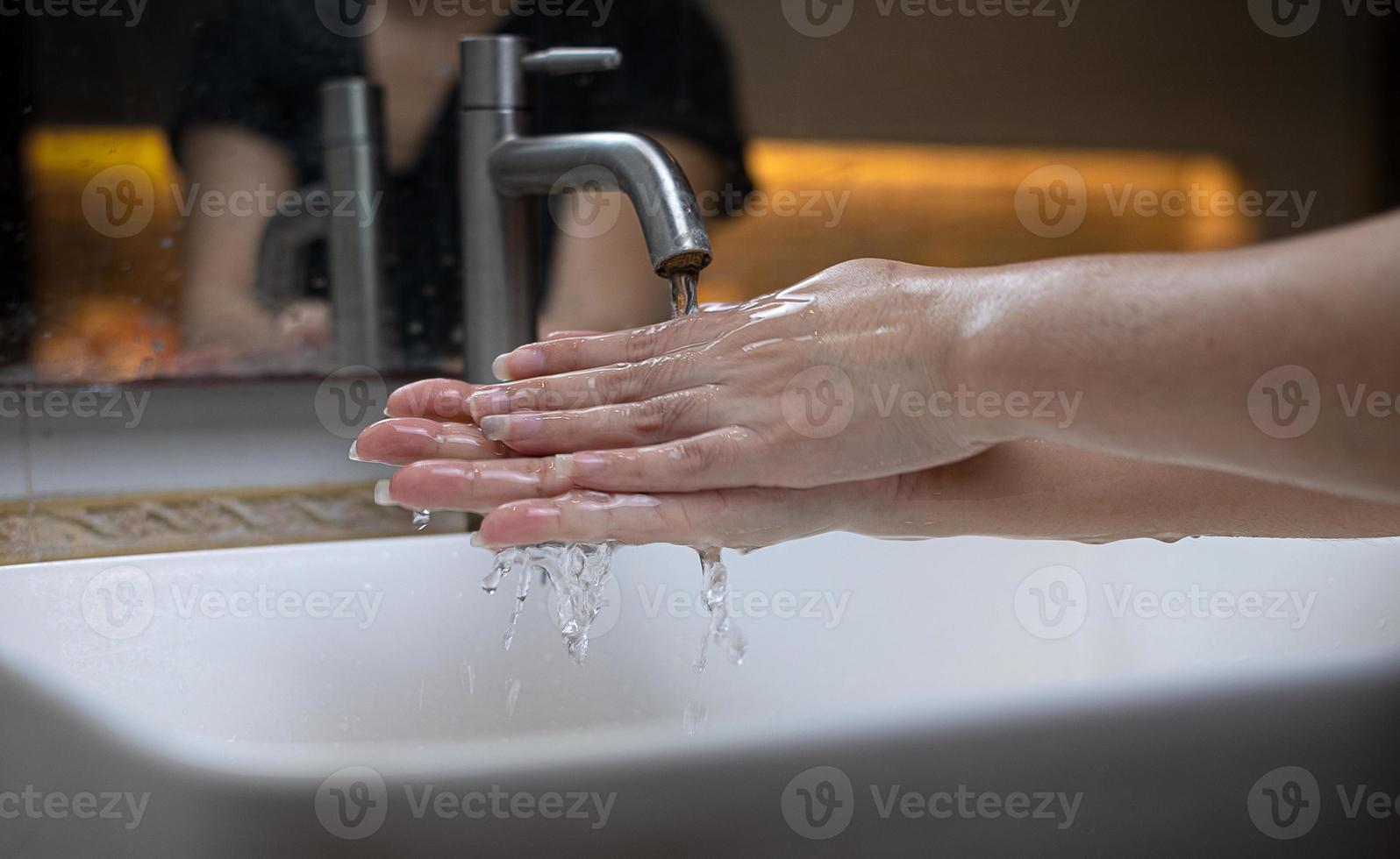 la hermosa mano femenina que aplica jabón en el fregadero o anti-bacterias para evitar la propagación de gérmenes en el fondo blanco foto