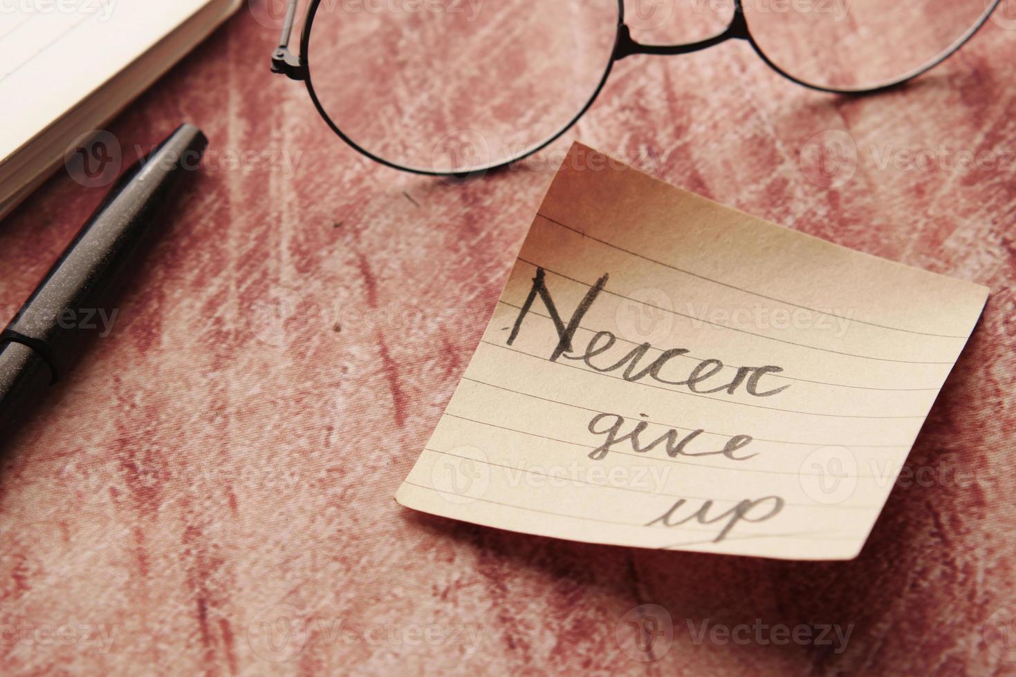 never give up word on stick note on table , photo