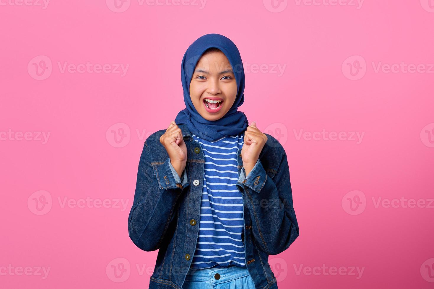 Retrato de mujer asiática joven emocionada celebrando el éxito con los brazos levantados foto