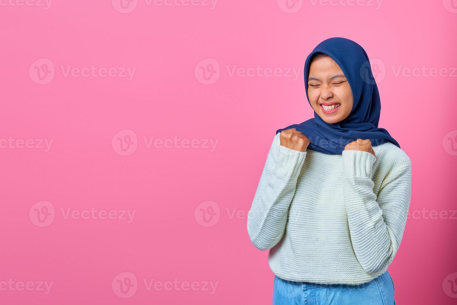 Retrato de mujer asiática joven emocionada celebrando el éxito con los brazos levantados foto