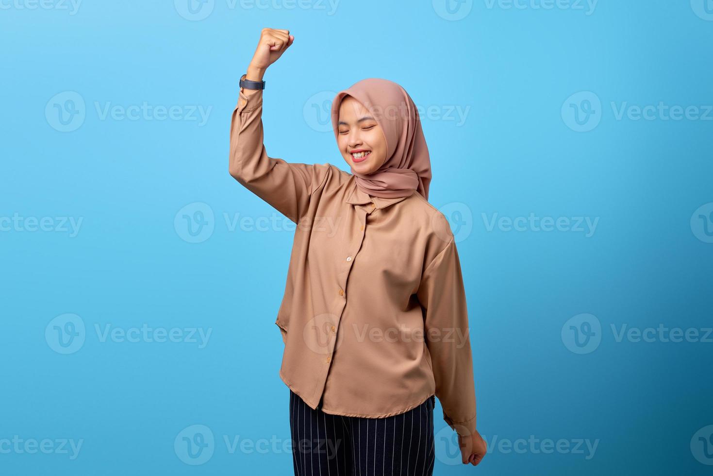 Retrato de mujer asiática joven emocionada celebrando el éxito con los brazos levantados foto