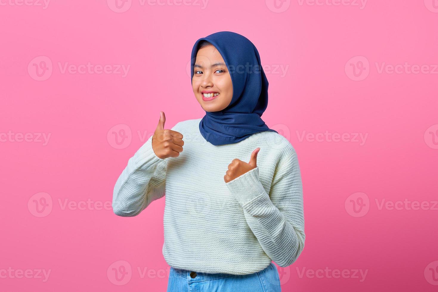 Portrait of smiling beautiful Asian woman showing thumbs up or approval sign photo