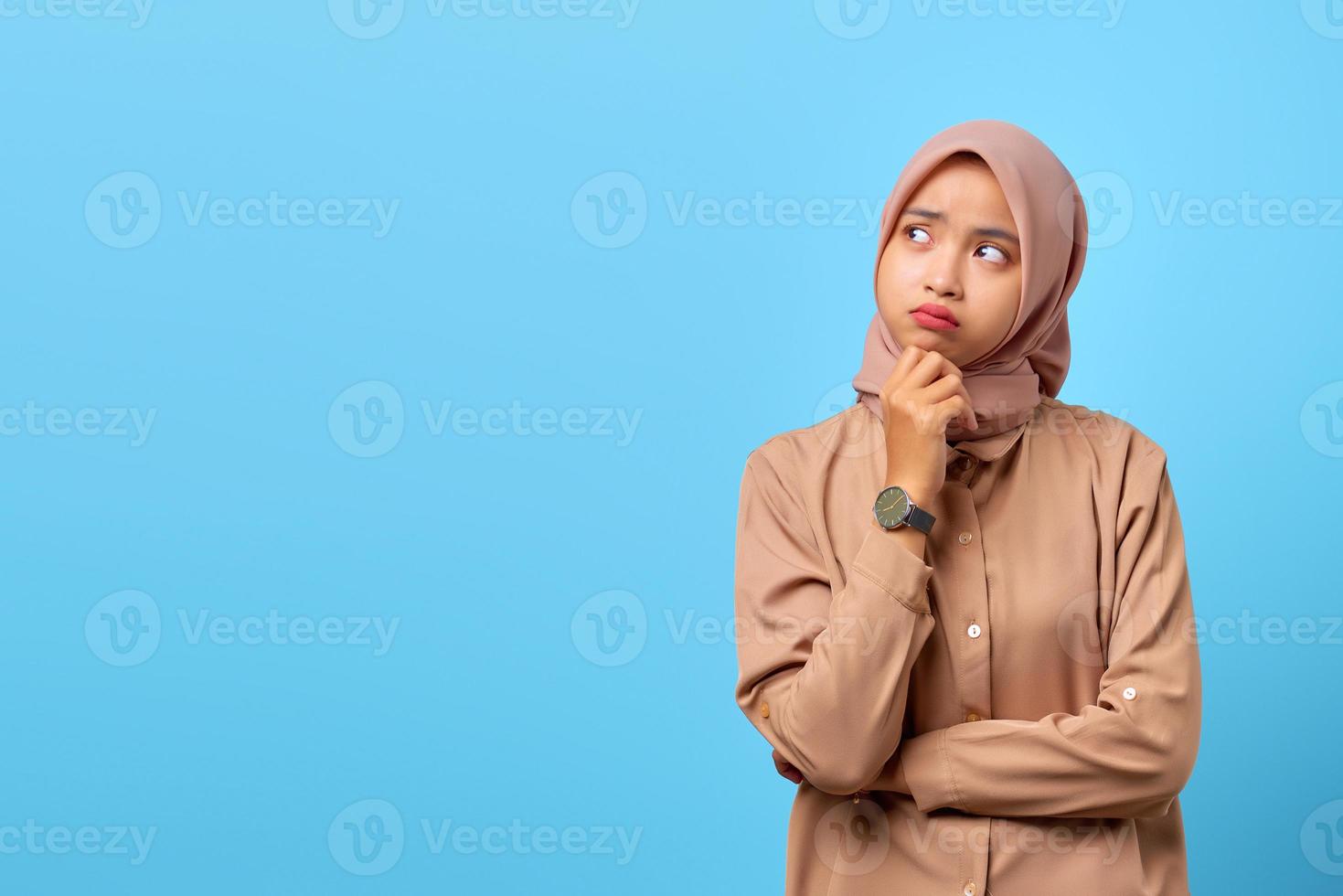 Portrait of young Asian woman thinking about question with hand on chin photo