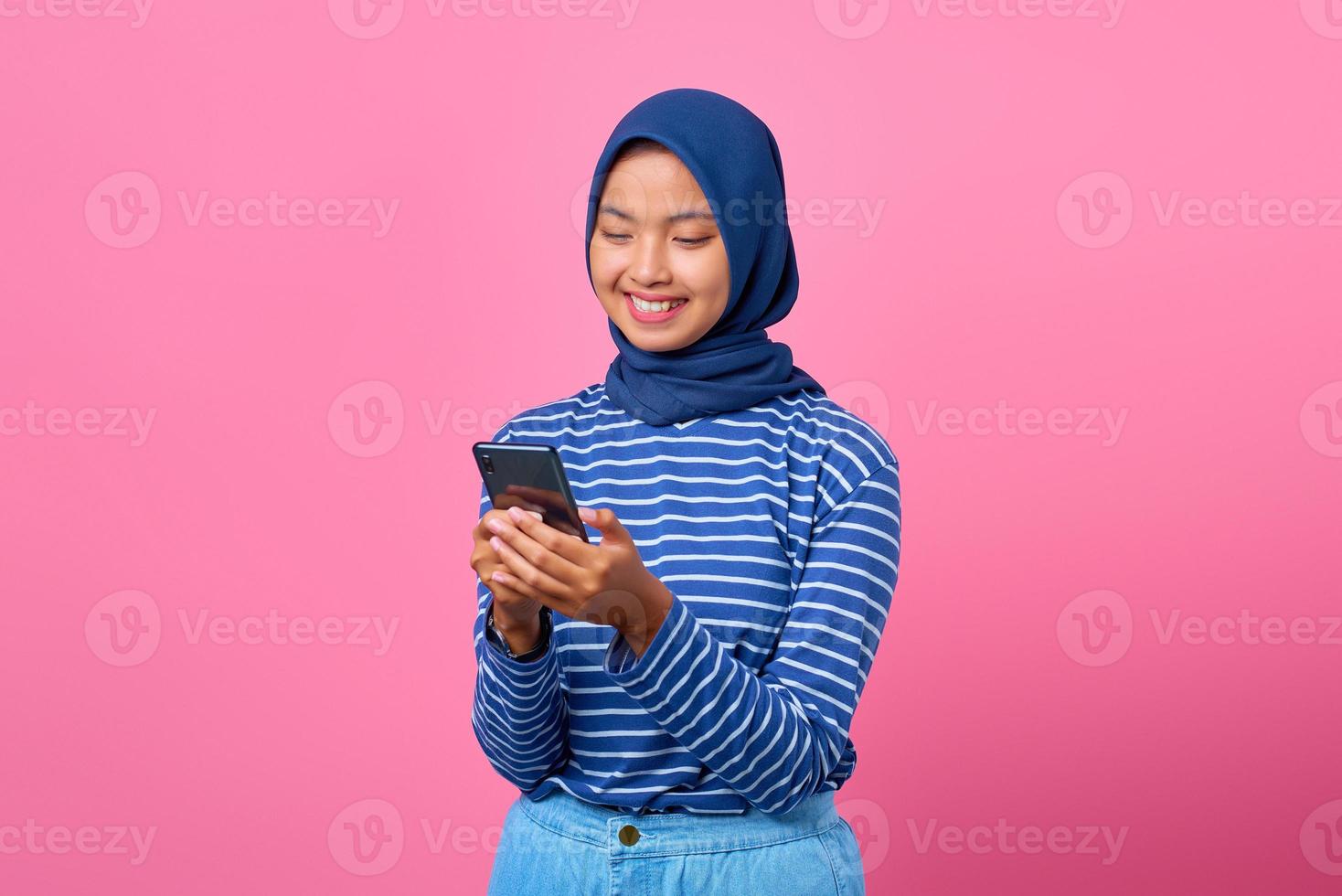 retrato, de, feliz, joven, mujer asiática, utilizar, teléfono móvil, en, fondo rosa foto