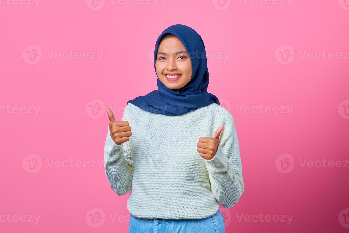 Portrait of cheerful young Asian woman showing thumbs up or approval sign photo