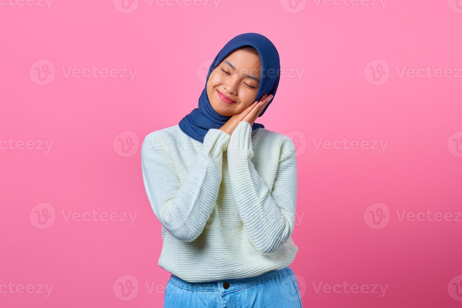 Portrait of beautiful young Asian woman with sleeping gesture on pink background photo