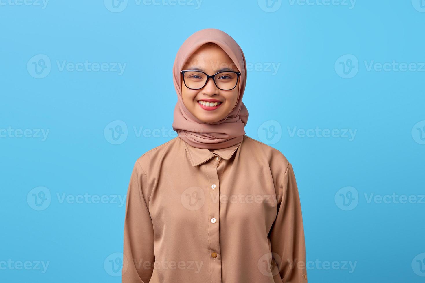 retrato, de, sonriente, joven, mujer asiática, llevando, anteojos, en, fondo azul foto