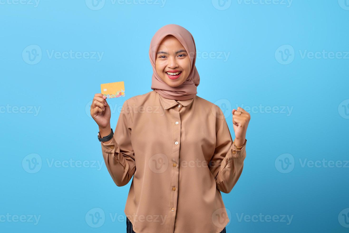 Portrait of excited cheerful young Asian woman celebrating luck with credit card on hand photo