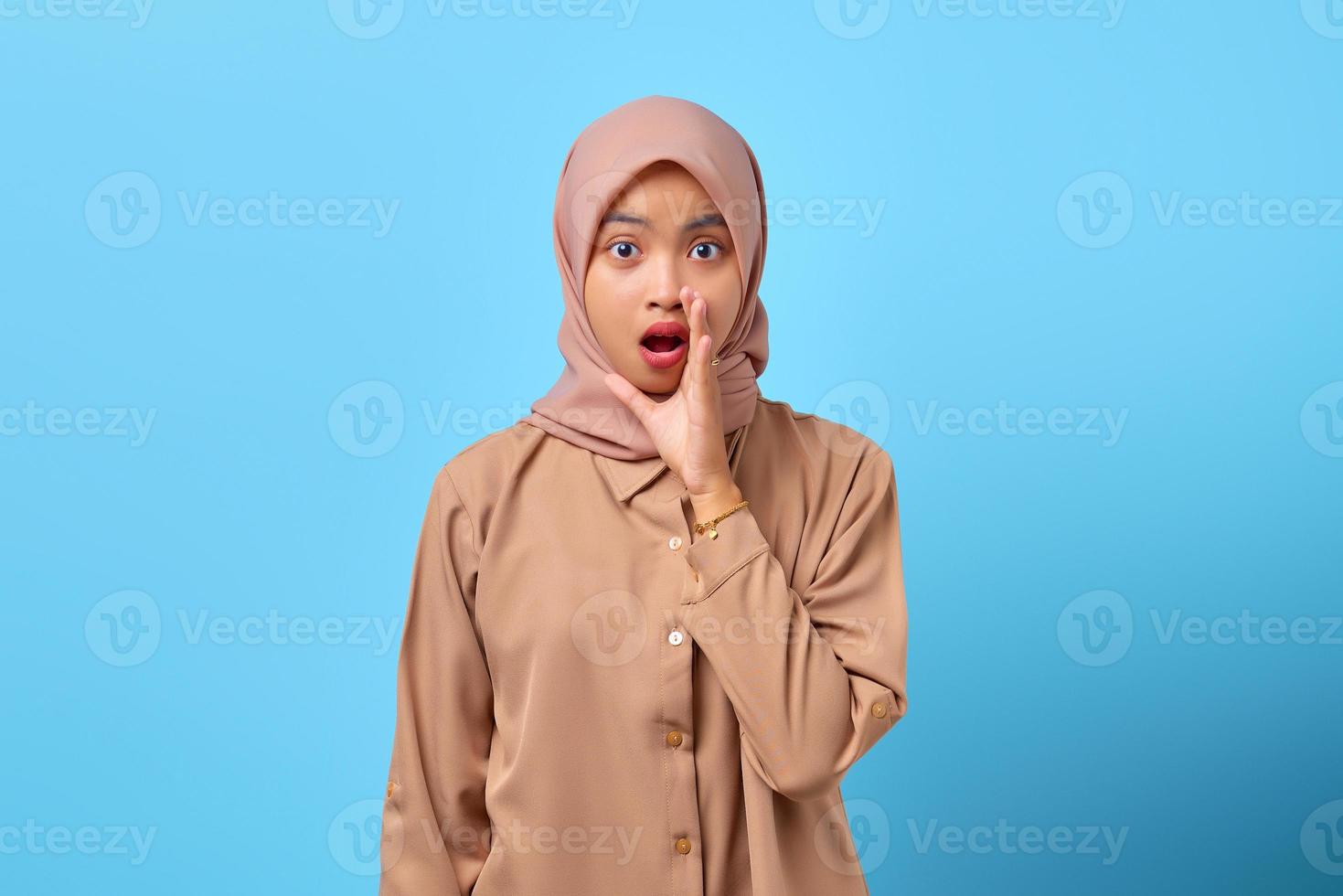 Portrait of surprised young Asian woman with open mouth and raised hand on face photo