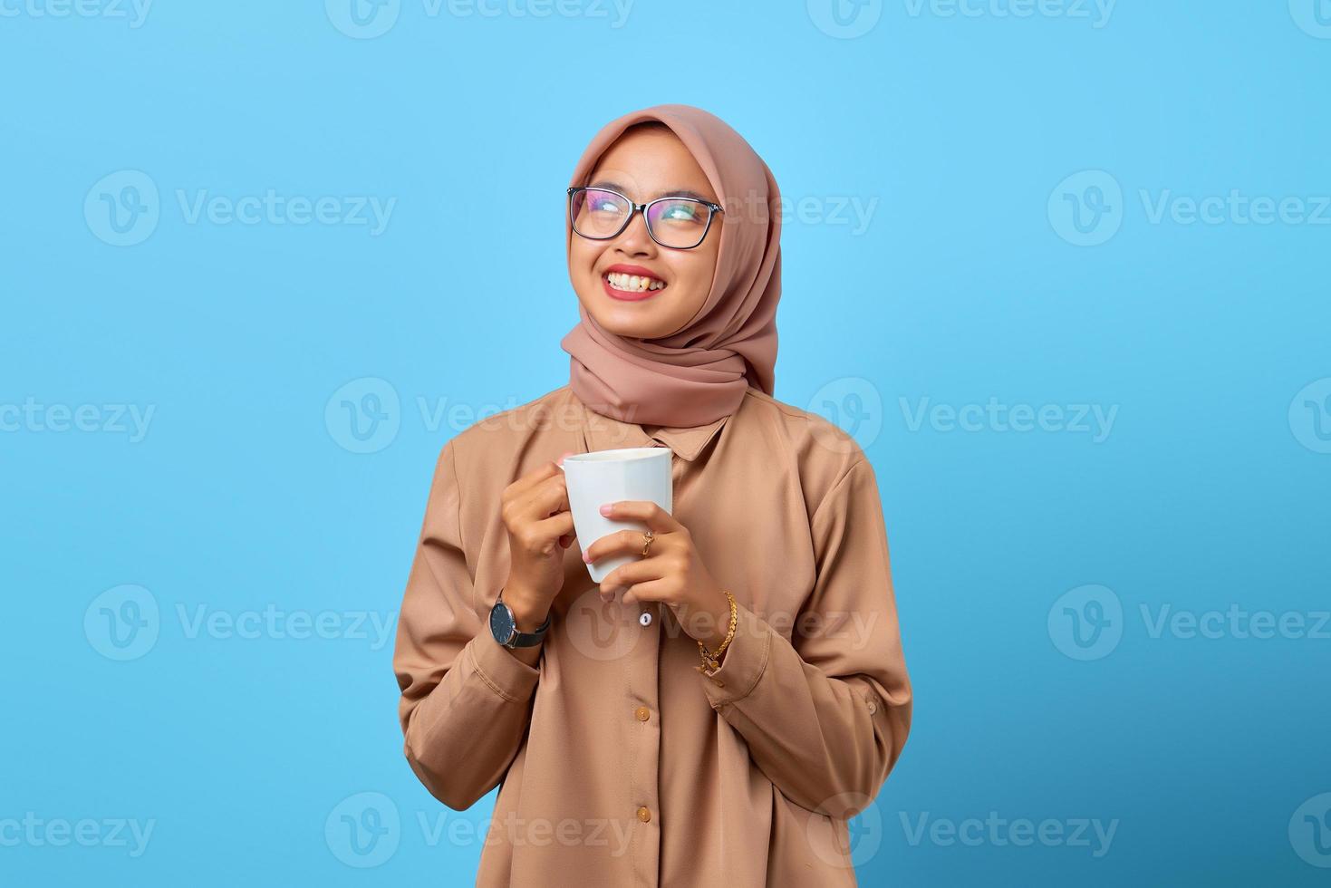 retrato, de, felicidad, joven, mujer asiática, asimiento de la mano, taza, encima, fondo azul foto