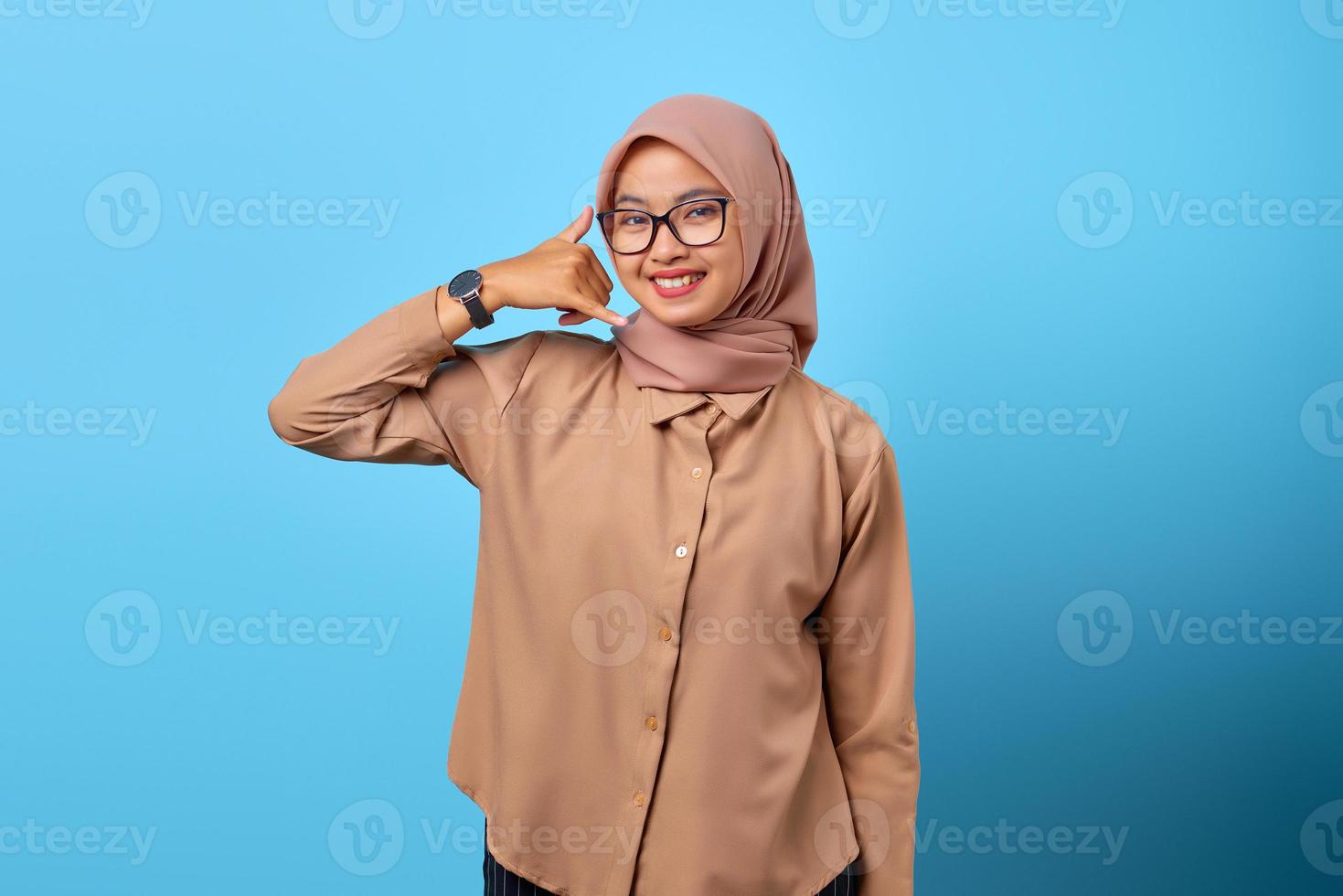 Portrait of smiling young Asian woman doing phone gesture with finger hands photo