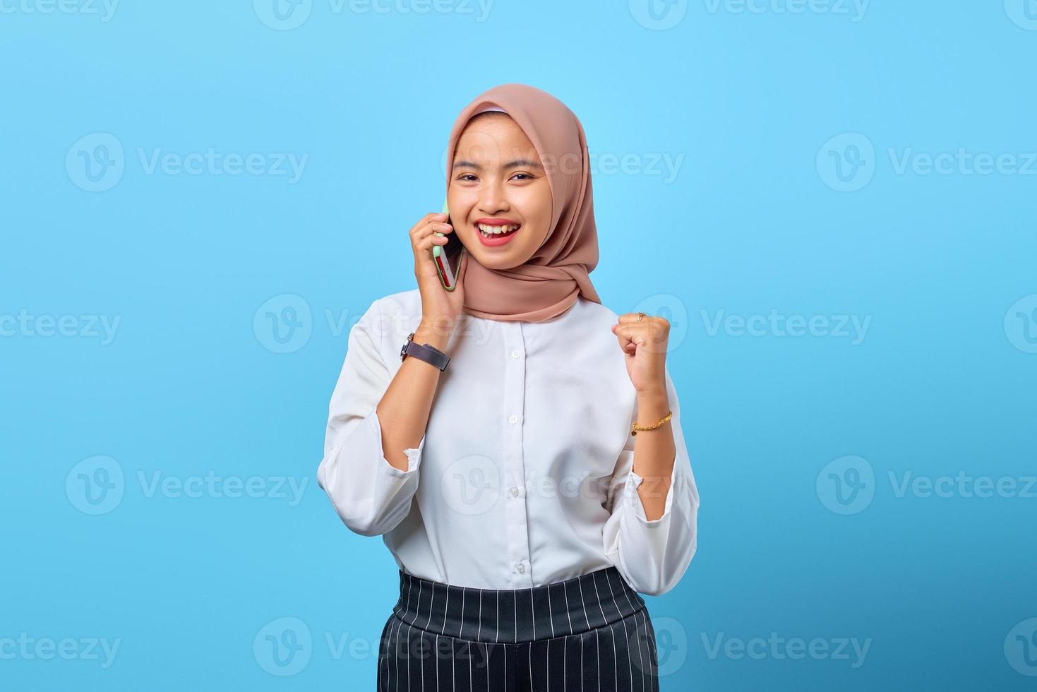 Retrato de mujer asiática joven alegre hablando por teléfono móvil con la celebración del éxito foto