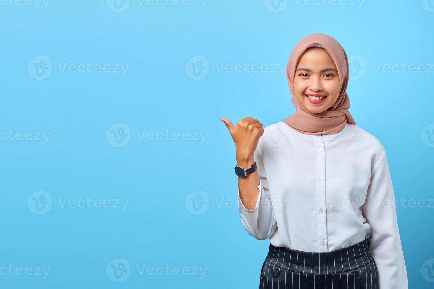 Portrait of smiling young Asian woman pointing to empty space with finger photo