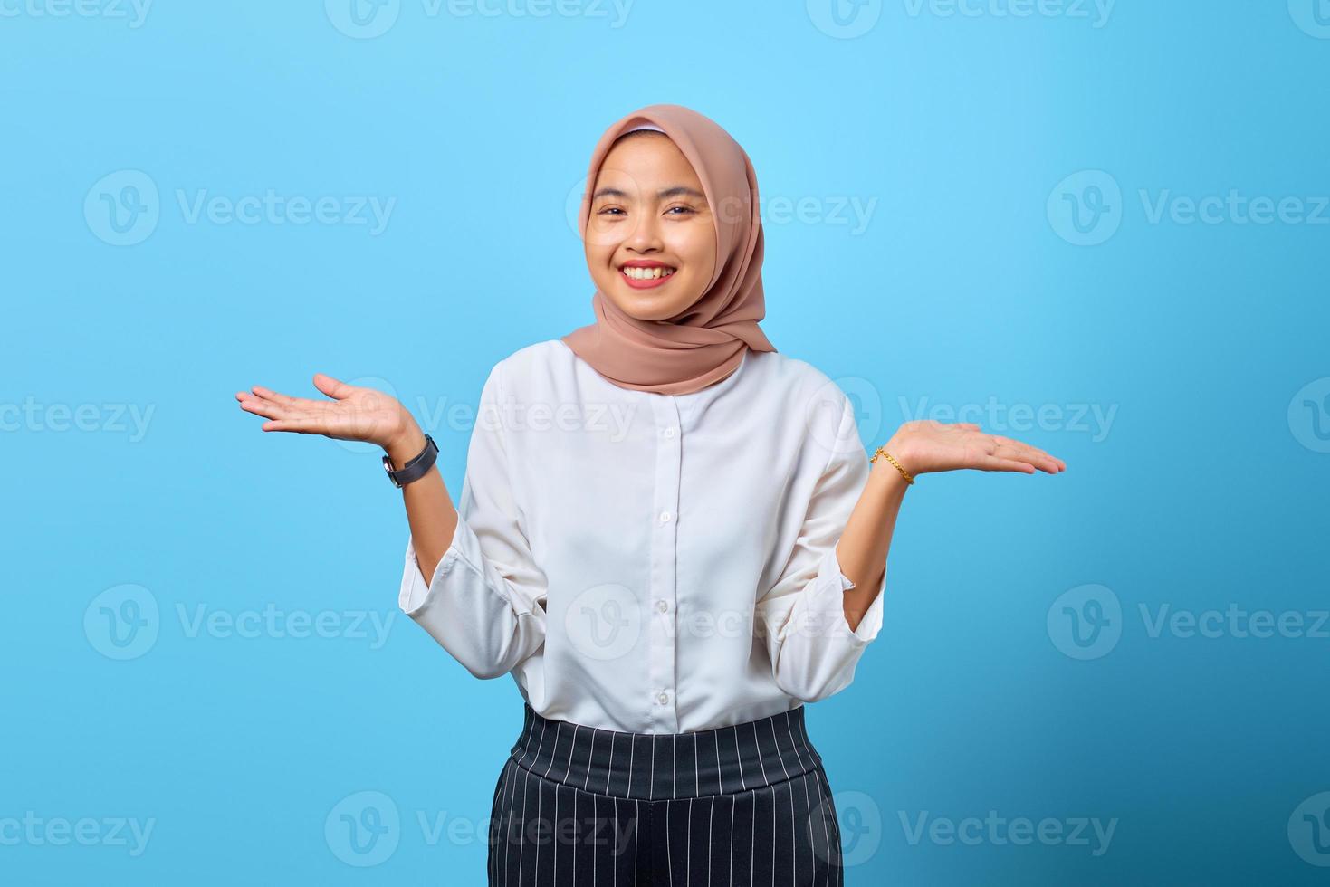 Retrato de joven alegre mujer asiática mantenga la mano presente anuncios promo sobre fondo azul. foto