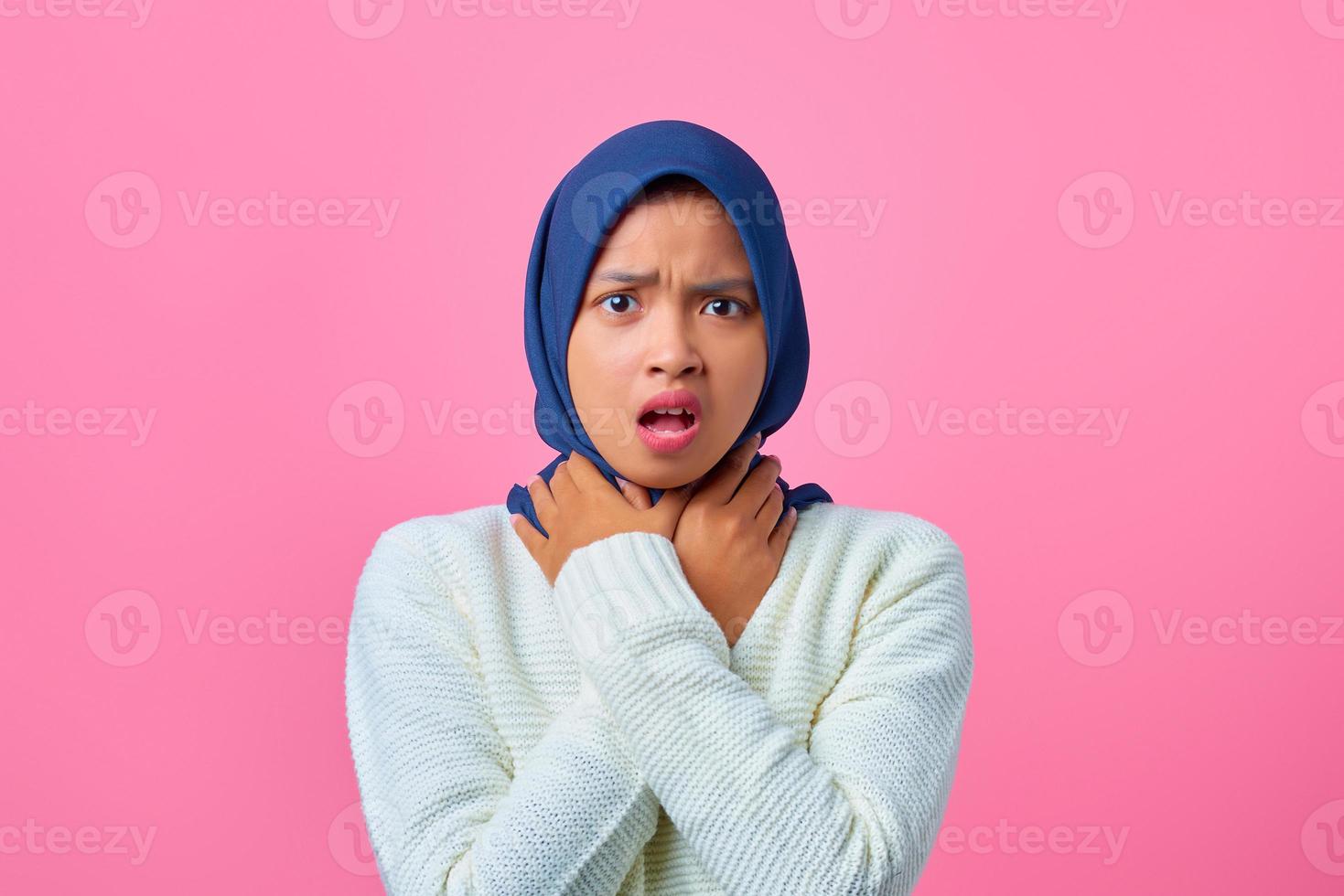 Retrato de joven mujer asiática sofocar porque doloroso estrangulamiento sobre fondo de color rosa foto