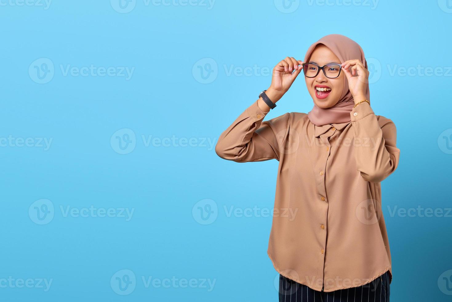 Portrait of cheerful young Asian woman hand touching glasses looking empty space photo