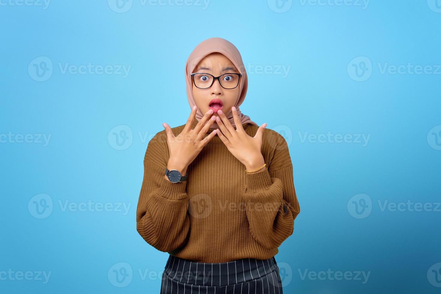 Portrait of surprised beautiful Asian woman with open mouth on blue background photo