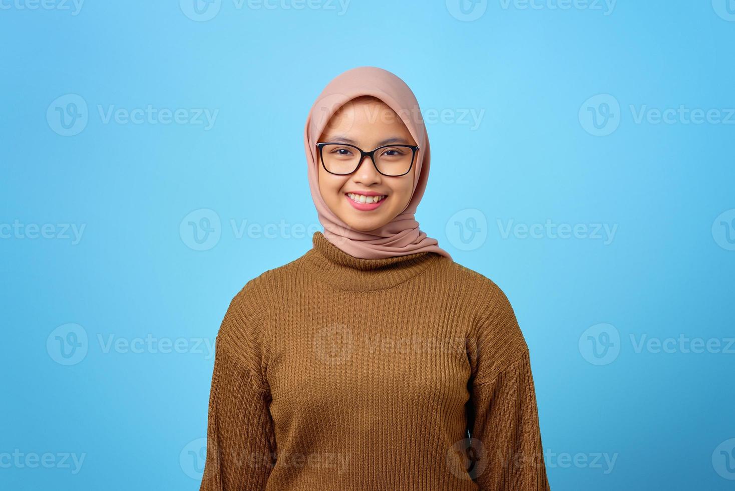 Portrait of happy young Asian woman with smiling face on blue background photo
