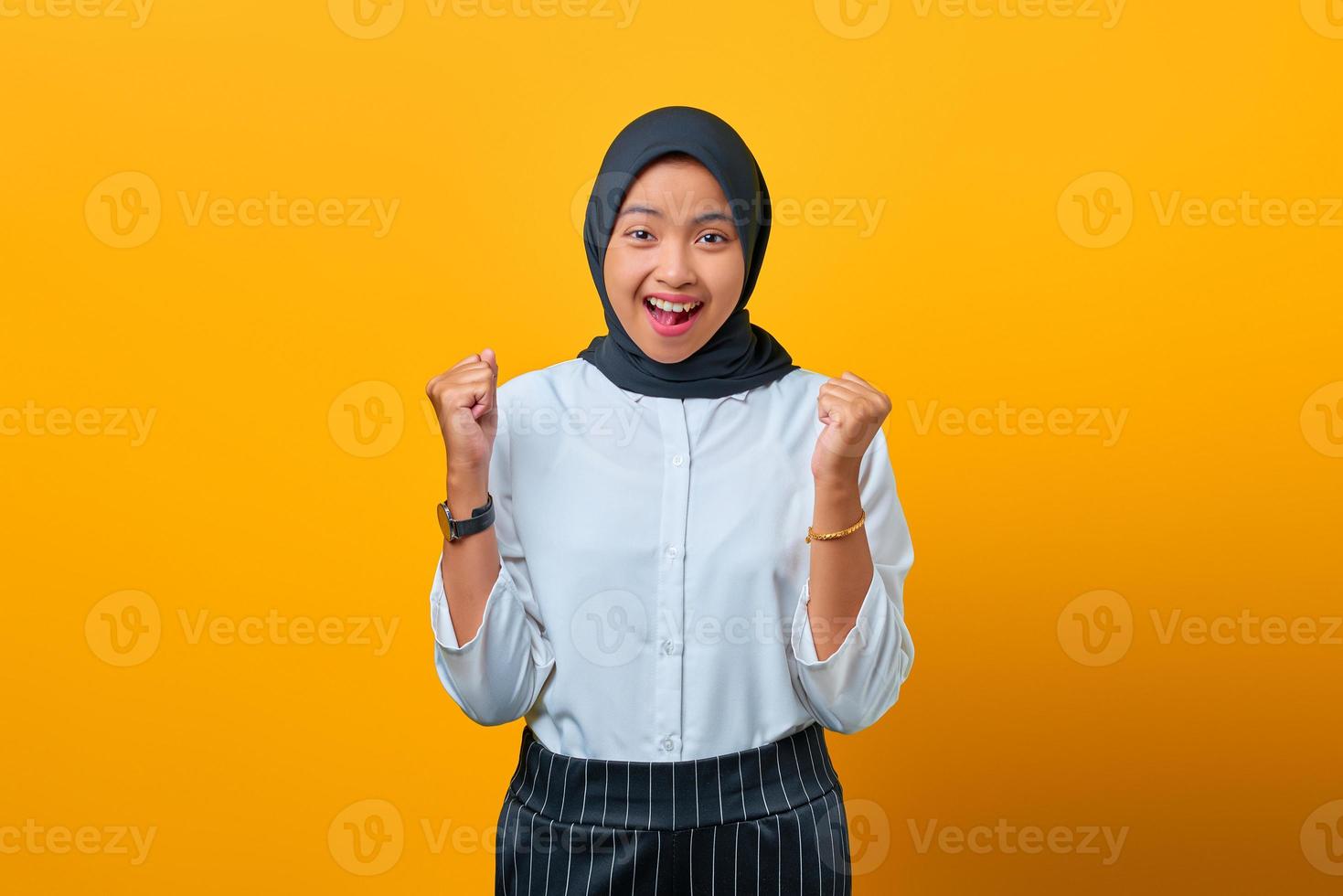 Retrato de mujer asiática hermosa emocionada celebrando el éxito sobre fondo amarillo foto