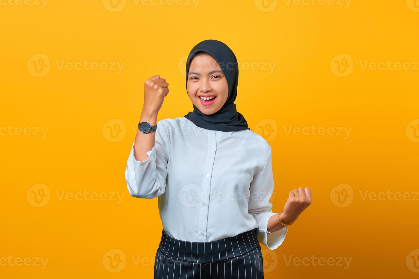 Retrato de hermosa mujer asiática emocionada regocijándose celebrando la suerte sobre fondo amarillo foto