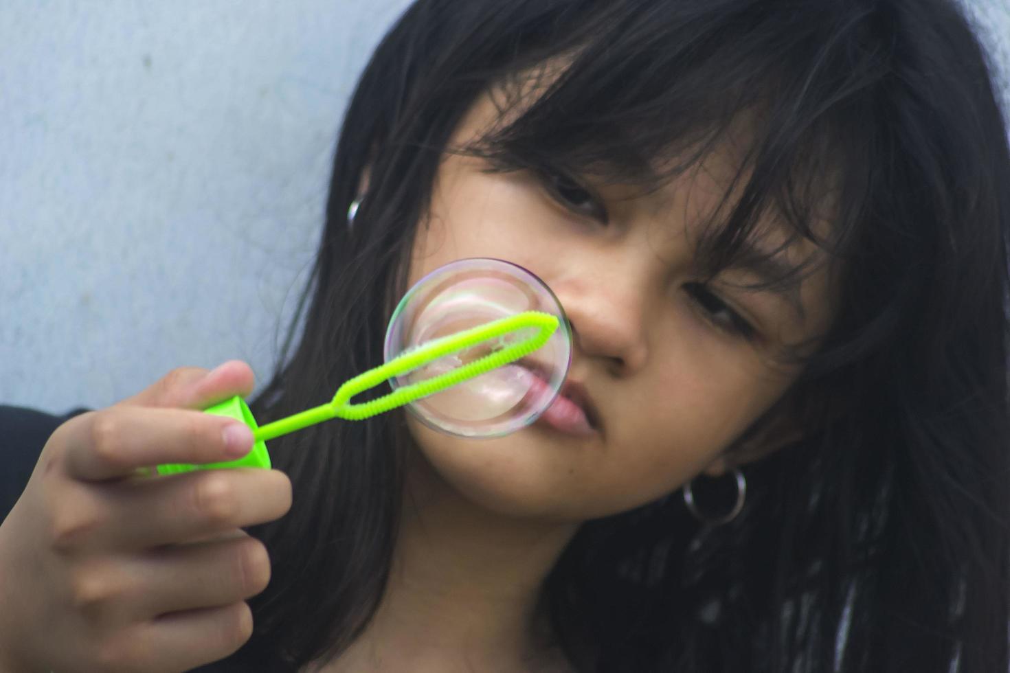 una niña que sostiene una máquina de hacer burbujas y las sopla. foto