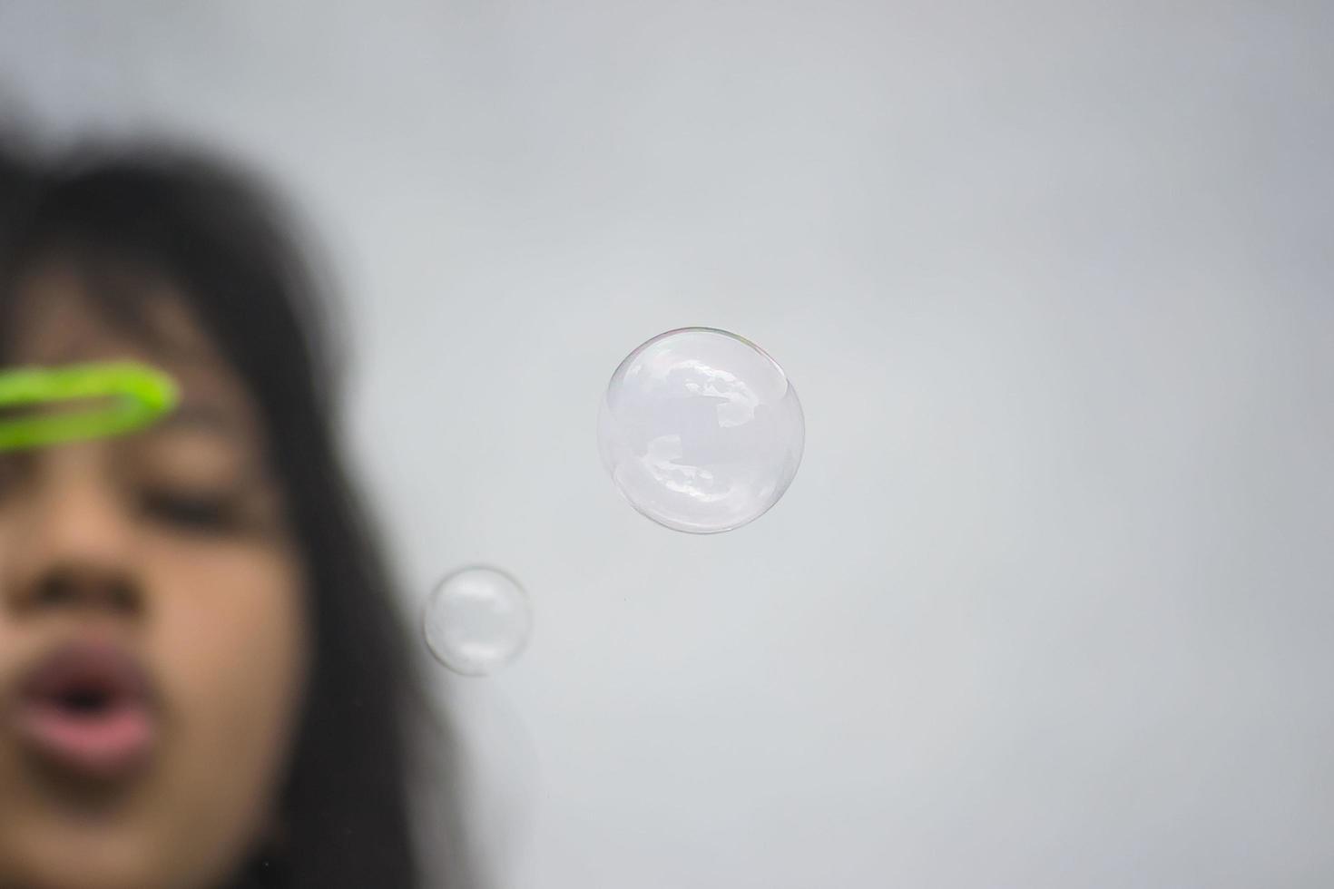 A girl holding a bubble maker and blowing them out. photo