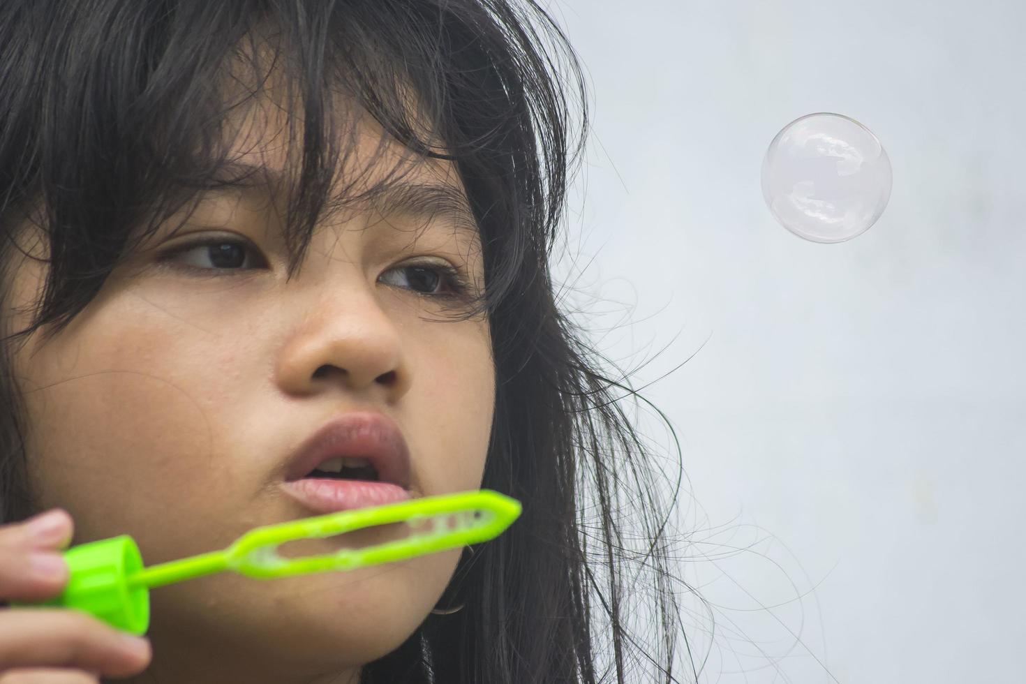 una niña que sostiene una máquina de hacer burbujas y las sopla. foto