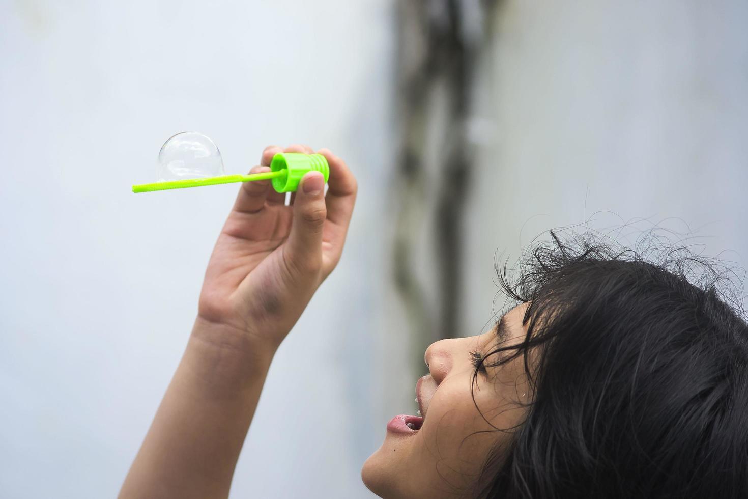 una niña que sostiene una máquina de hacer burbujas y las sopla. foto