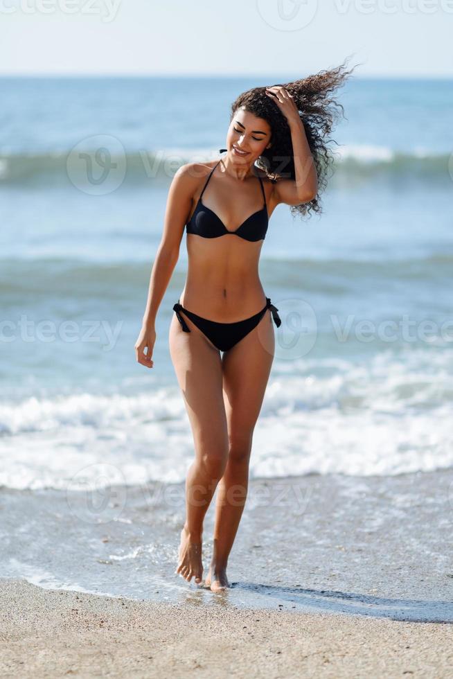 Young arabic woman with beautiful body in swimwear on a tropical beach. photo