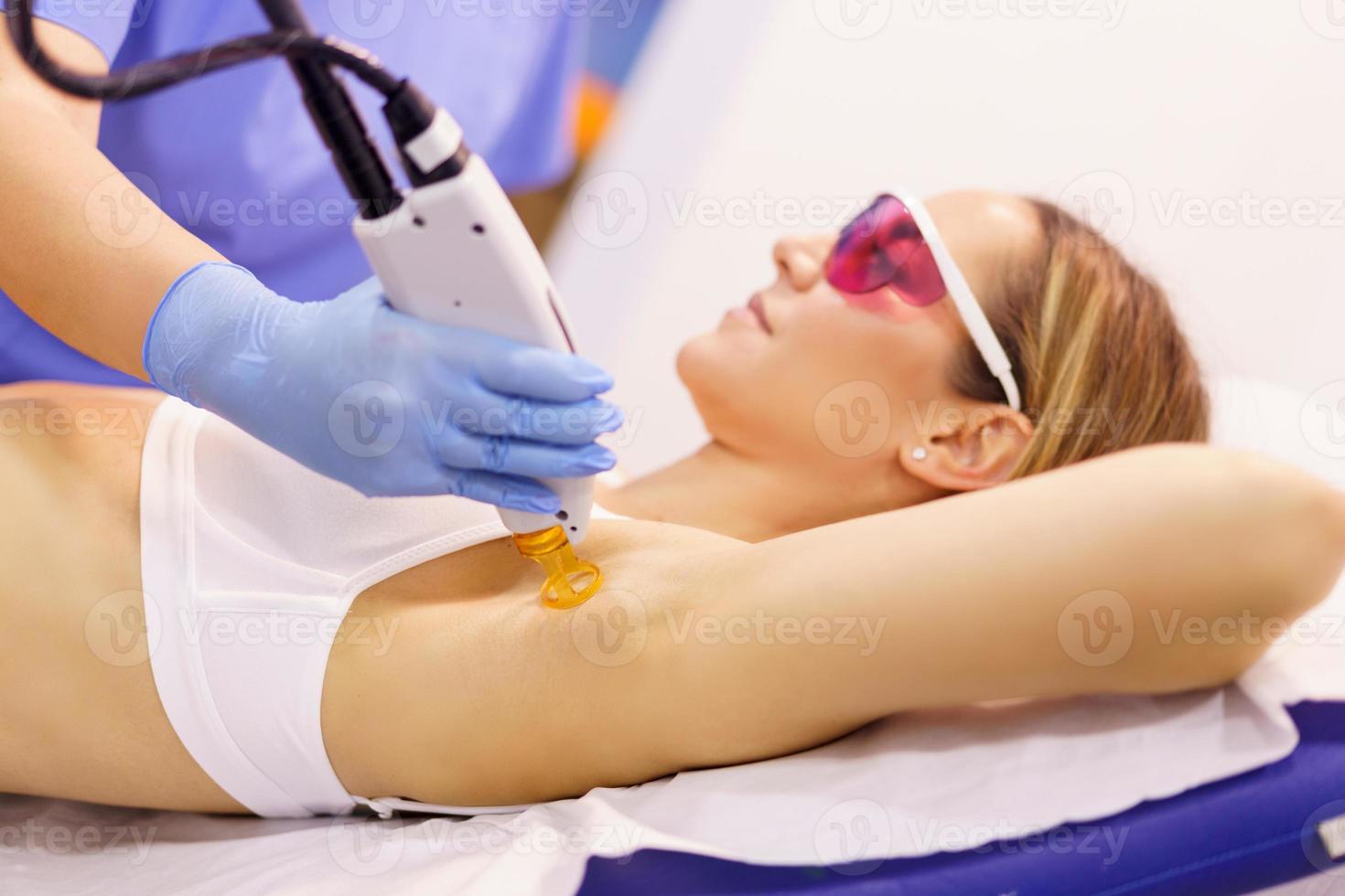 Woman receiving underarm laser hair removal at a beauty center. photo