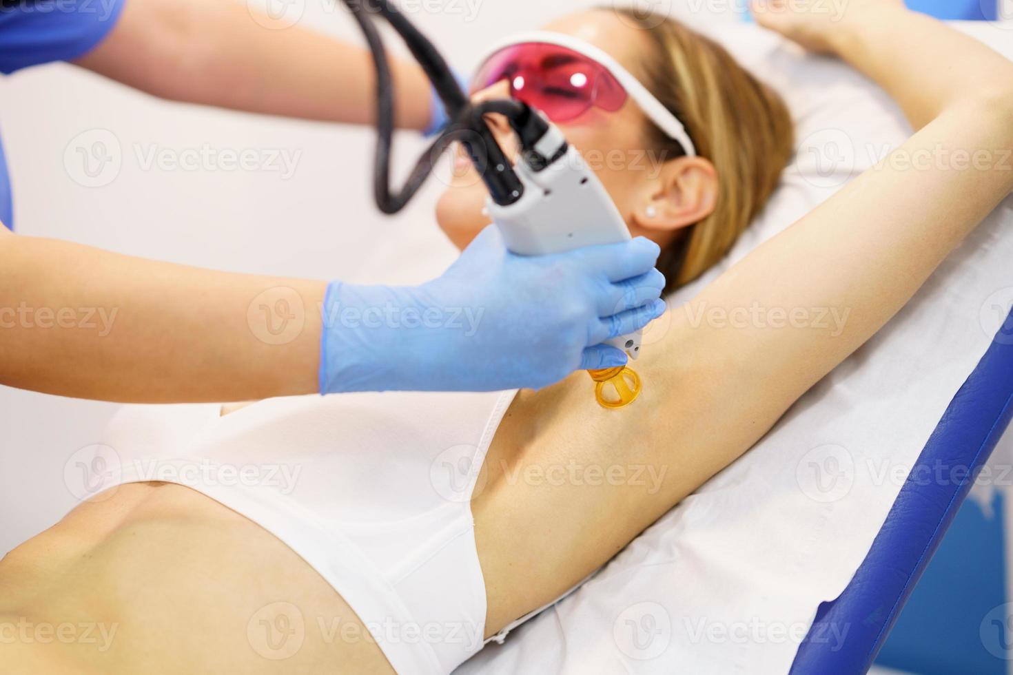 Woman receiving underarm laser hair removal at a beauty center. photo