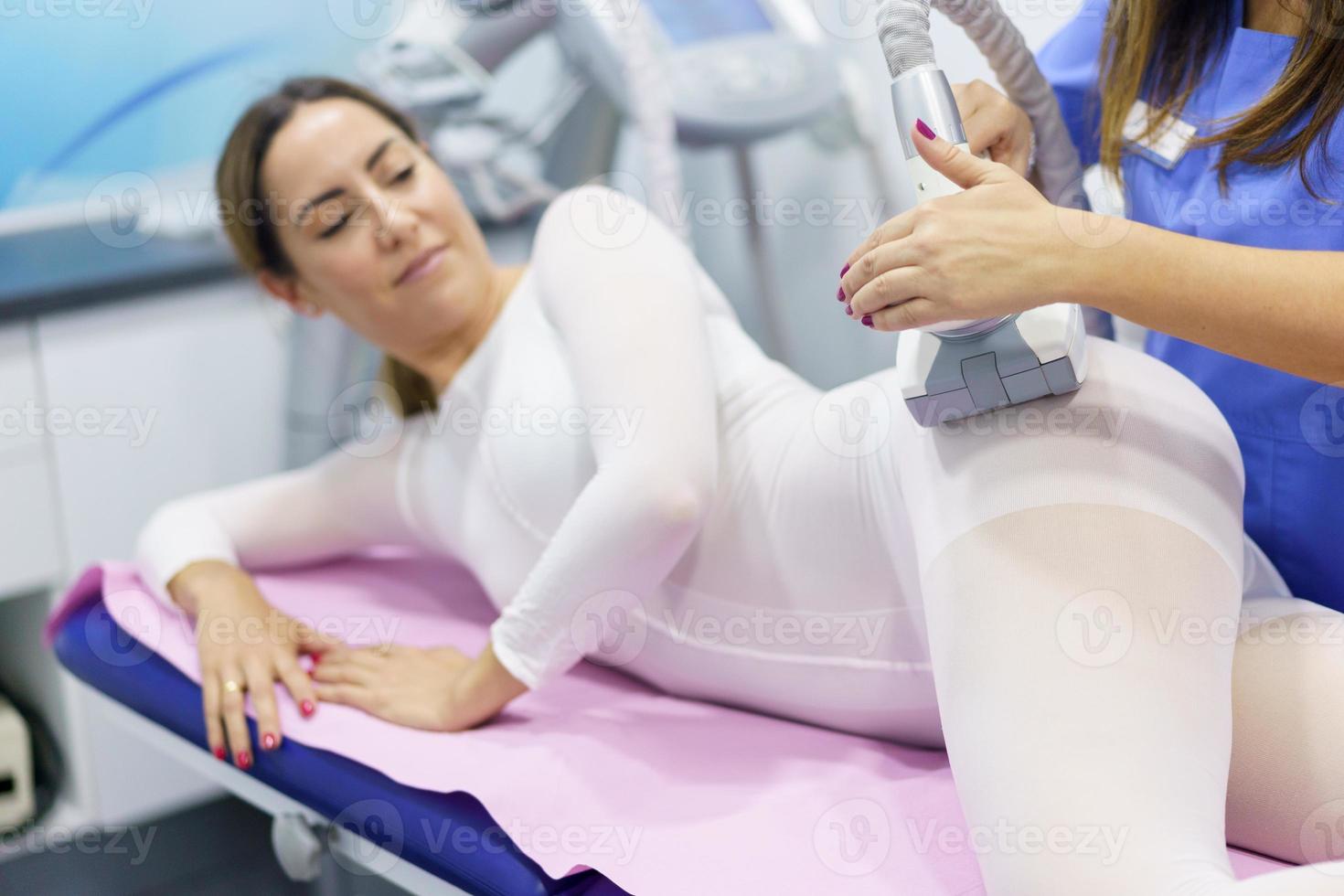 Mujer en traje blanco especial con un masaje anticelulítico con aparato de spa foto