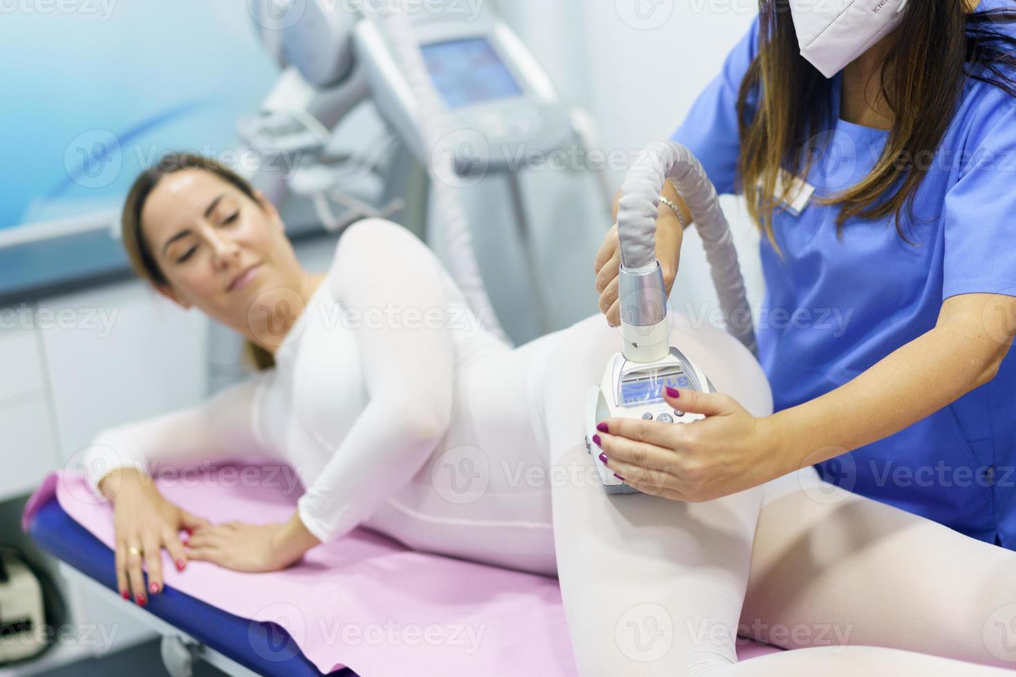 Mujer en traje blanco especial con un masaje anticelulítico con aparato de spa foto