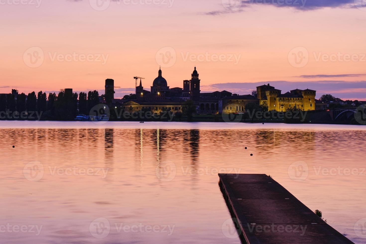 Medieval castle and city skyline illuminated at sunset photo