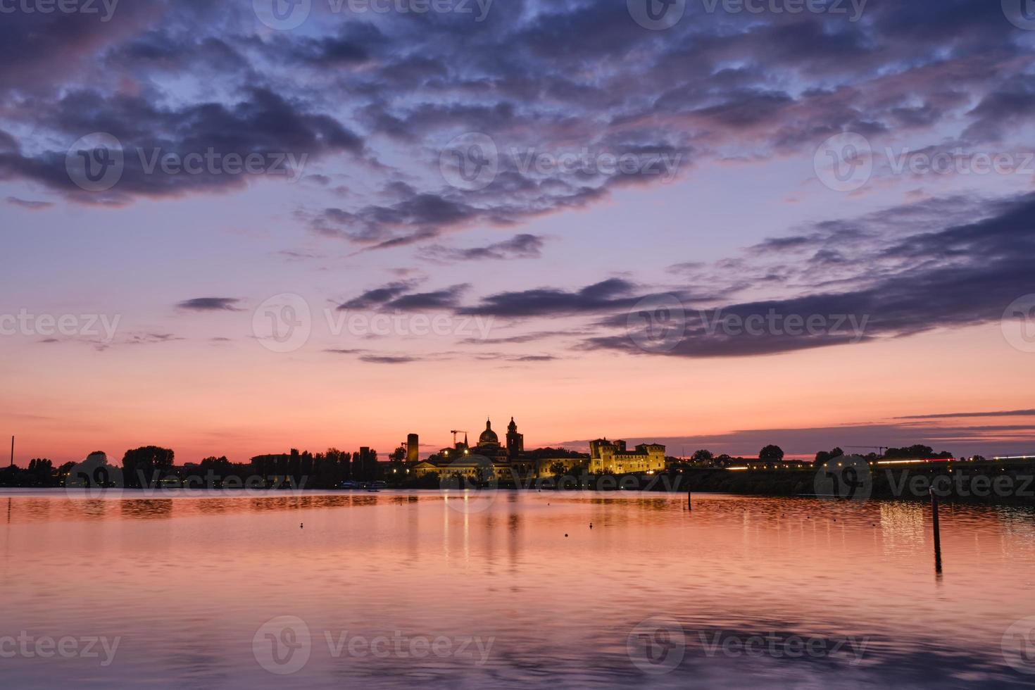 Medieval castle and city skyline illuminated at sunset photo